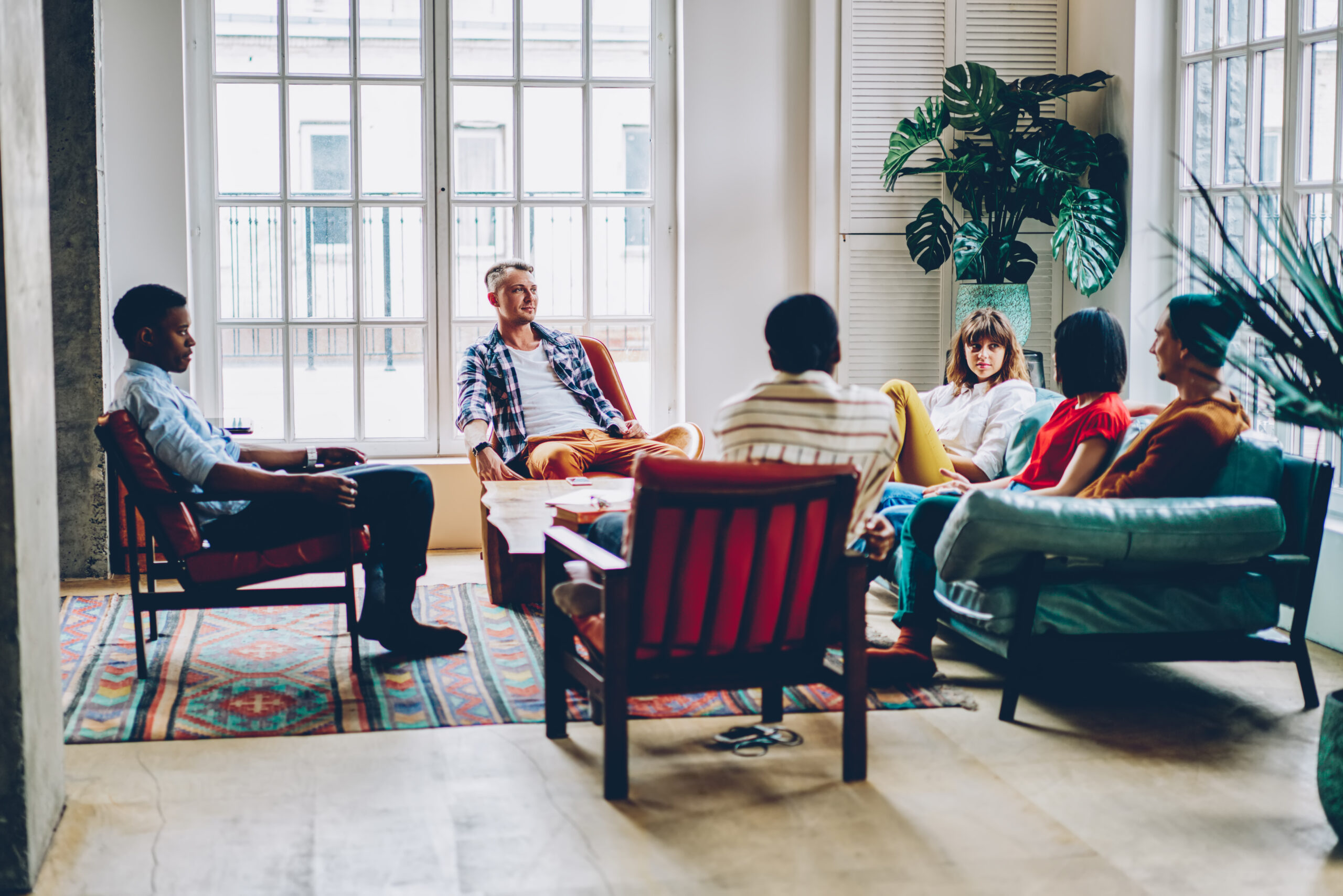 Group of multicultural young people resting in comfortable hostel and playing game in free time.Diverse hipster friends enjoying communication with each other sitting in modern apartment